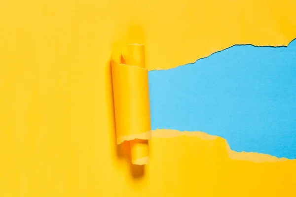 Trozo roto de papel amarillo sobre fondo azul — Foto de Stock