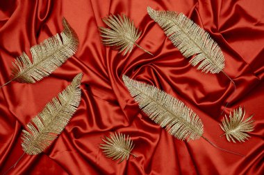 Kırmızı tekstil zemininde dekoratif altın yapraklar