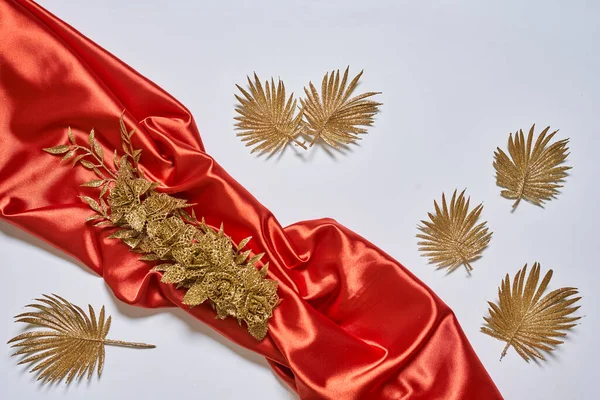 Decorative golden leaves on red textile backdrop — Stockfoto