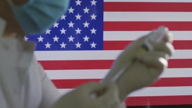 Sağlık çalışanı, Amerikan bayrağına karşı covid-19 aşısı hazırlayın.