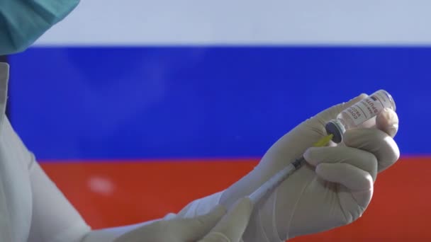 医療従事者は、ロシアの旗に対するcovid-19ワクチンの注射を準備する — ストック動画