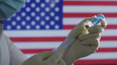 Sağlık çalışanı, Amerikan bayrağına karşı covid-19 aşısı hazırlayın.