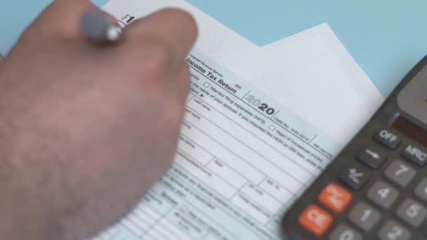 Uma pessoa calcula impostos e preenche 1040 Formulário de Imposto — Vídeo de Stock