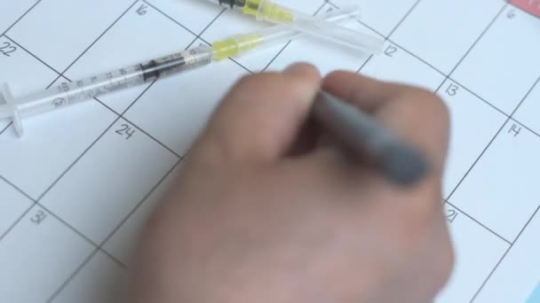 Uma pessoa escrevendo no lembrete de calendário - dia da vacina — Vídeo de Stock