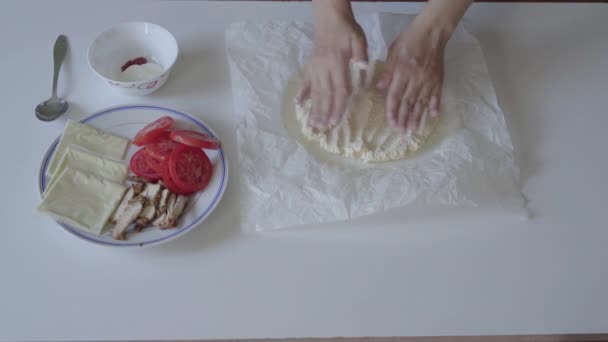 Готовим тесто для пиццы на белом кухонном столе — стоковое видео