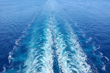 The wake left by a vessel creates a path in the water, symbolizing progress, a forward journey, and the direction toward a new destination.