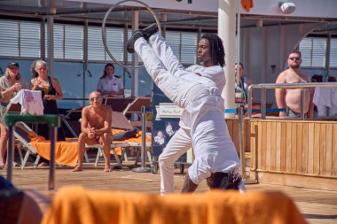 Venecia. Italia - October 11, 2025: Two male acrobats perform a balancing act with a hoop to entertain tourists on the sunny deck of a cruise ship during their voyage.