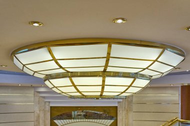 Large, opulent Art Deco style ceiling lamp. The golden brass structure and frosted glass panels create a warm, diffused light perfect for luxury interiors.