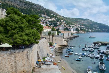 Dubrovnik 'teki Pile Bay' in göz kamaştırıcı manzarası. Tekneler antik şehir duvarlarının yanındaki turkuaz sularda demirli, yamaçta şehir ve bir kafe var..
