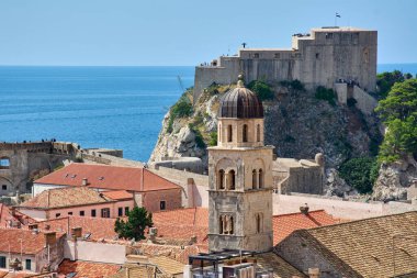Hırvatistan 'ın Dubrovnik kentinin ikonik manzarası. Lovrijenac Kalesi Adriyatik Denizi 'nin kıyısında, tarihi bir çan kulesi ve ön planda terracotta çatıları var.