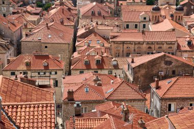 Dubrovniks 'in eski kasabasındaki yoğun şehir manzarasının yüksek açılı görüntüsü. İkonik terasotta çatıları ve tarihi taş binalar tarihi bir düzen oluşturuyor.