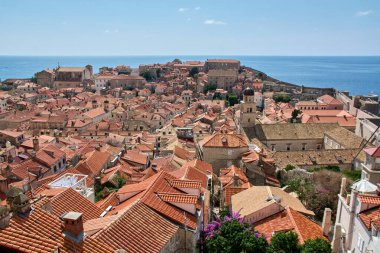 Hırvatistan 'ın Dubrovniks kentindeki turuncu terasotta çatılarının çarpıcı panoramik manzarası. Mavi Adriyatik Denizi ufukta görünüyor.