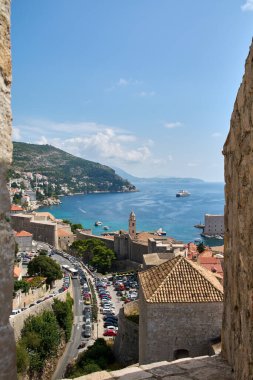 Hırvatistan 'ın Dubrovnik kentinin çarpıcı yüksek açılı manzarası, tarihi terracotta çatıları, mavi Adriyatik Denizi ve körfeze demir atmış büyük bir yolcu gemisi sergileniyor..