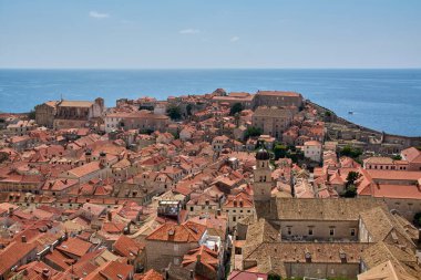Klasik bir Dalmaçya kıyı manzarası. Dubrovniks Eski Kasabası ortaçağ mimarisini, kilise kulelerini ve açık gökyüzünün altındaki kırmızı çatıları gösteriyor..