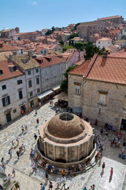 Turistlerin yüksek açılı manzarası tarihi Onofrios Büyük Pınarı 'nın etrafında toplandı. Dubrovniks Eski Kasabası 'nda insanlar kireçtaşı kaldırımında yürüyor.