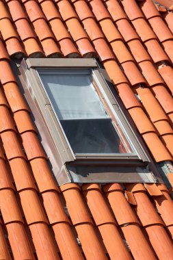 Modern tavan penceresi olan turuncu bir terracotta çatısının yakın çekim detayları. Geleneksel mimari, inşaat, yenileme ve konut kavramının deseni ve dokusu.