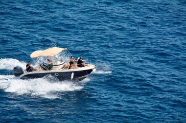 Dubrovnik. Hırvatistan - 20 Kasım 2025: Bir grup arkadaş mavi denizde sürat yapan bir teknede eğleniyor. Yaz tatilinde güneşin ve özgürlüğün tadını çıkarırken tekne bir uyanış yaratıyor..