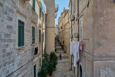 Dubrovnik 'te yüksek açılı bir ara sokak. Çamaşır ipinde kurumuş çamaşır ve tarihi bir kasabada merdivenlerden çıkan bir kişi..