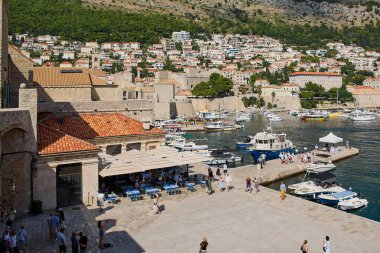 Dubrovnik. Hırvatistan - 20 Kasım 2025: Tarihi limanda tekneli ünlü Dubrovnik şehri. Güneşli bir yaz gününde Dalmaçya kıyılarında popüler bir UNESCO turizm beldesi.