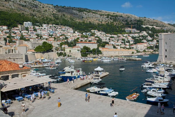 Dubrovnik. Hırvatistan - 20 Kasım 2025: Hırvatistan 'ın Dubrovnik kentindeki Eski Liman' ın yüksek açılı manzarası. Arka planda tekneler, şehir duvarları ve Srd Dağı ile rıhtımda yürüyen turistler görülüyor..