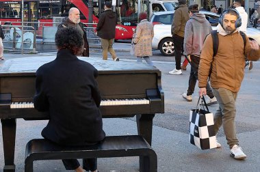 Barselona 'da. İspanya - 10 Ocak 2026: Şehir merkezinde insanlar yürürken bir sokak piyanisti kalabalık bir yaya bölgesinde siyah bir kuyruklu piyano çalıyor.