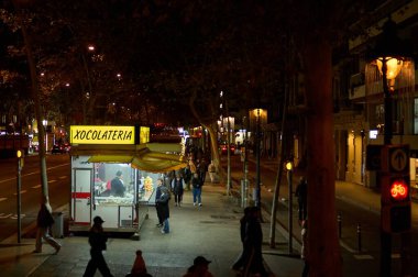 Barselona 'da. İspanya - 16 Ocak 2026: Barselona 'daki Xocolateria sokak tezgahı, yapraklı bir şehir bulvarında insanlara geleneksel çikolata ve churros servisi yapmaktadır..