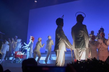 Barselona 'da. İspanya - 18 Ocak 2026: Haleli beyaz kostümlü ve kırmızı bebek arabalı aktörlerin mavi bir arkaplanda oynadığı dramatik sahne yapımı.