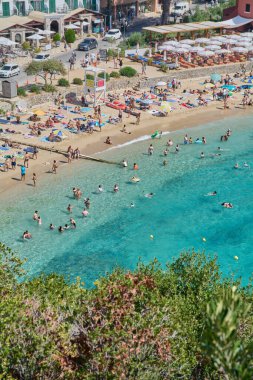 Korfu. Yunanistan - 22 Ocak 2026: Tatilcilerin el değmemiş İyon Denizi ve altın kumların tadını çıkardığı canlı bir Yunan kıyı şeridinin panoramik görüntüsü.