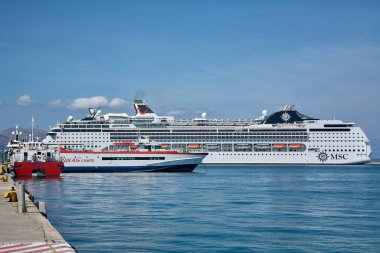 Korfu. Yunanistan - 29 Ocak 2026: Lüks yolcu gemileri ve bir yolcu feribotu durgun bir ada limanında dinlenirken, küresel turizm, deniz taşımacılığı ve Akdeniz seyahatinin ekonomik etkisini vurguluyor.