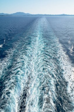 Güçlü bir geminin yüksek açılı görüntüsü açık gökyüzünün altında beyaz köpük desenli derin mavi deniz suyunda uyanır..
