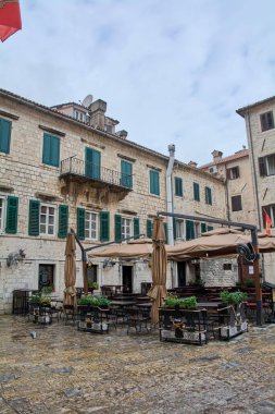 kotor. Montgomery - Şubat 07, 2026: Taştan binalar, yeşil kepenkler ve yağmurdan sonra boş kafe terasları olan tarihi eski kasaba meydanı, Avrupa mirası, turizm cazibesi ve sakin şehir atmosferi