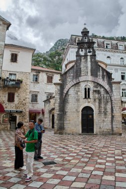 Kotor. Karadağ - 07 Şubat 2026: Tarihi eski kentin Aziz Luke Kilisesi yakınlarındaki ortaçağ meydanında duran turistler. Popüler Balkan kentinde bulutlu gökyüzünün altında Romanca mimari.