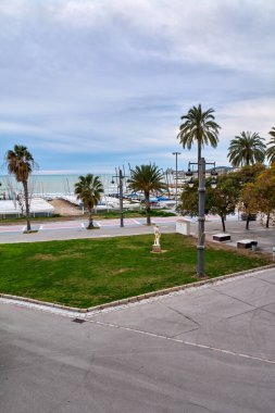 Siteler. İspanya - 17 Şubat 2026: Liman ve plaja bakan heykellerin bulunduğu liman parkı Sitges Katalonya 'da manzaralı bir kıyı manzarası yarattı