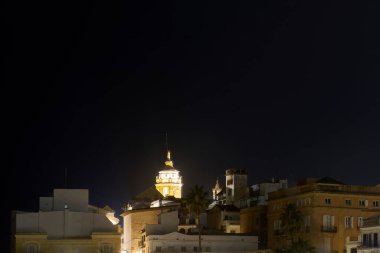 Sant Bartomeu ve Santa Tecla Kilisesi 'nin gece görüşü Akdeniz kıyısı üzerinde dalgalar ve tarihi binalarla aydınlandı.