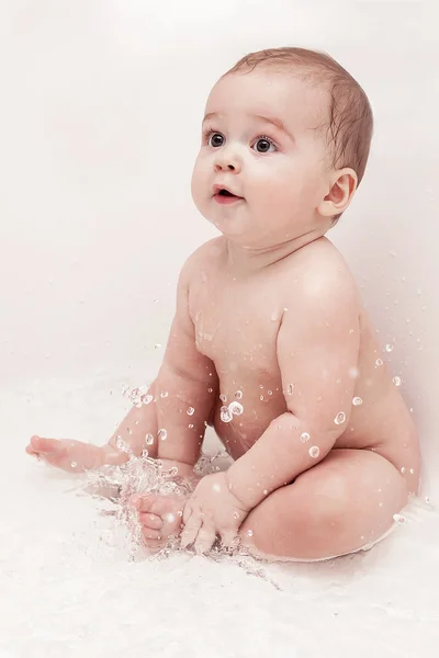 Child is sitting in a bath  and playing with splash — Stock Photo, Image