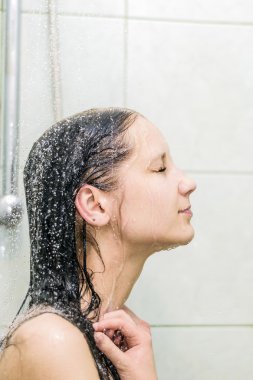 Kadın sıcak duş akışları altında rahat