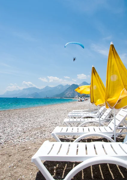 Sombrilla amarilla, tumbona y parapente en la playa — Foto de Stock