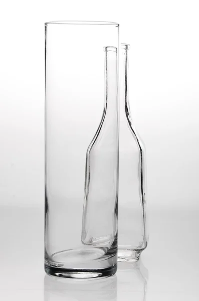Um copo e uma garrafa em um fundo branco cinza — Fotografia de Stock