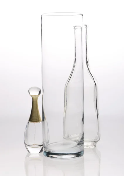 Стекло, графин и бутылки духов на сером белом фоне — стоковое фото