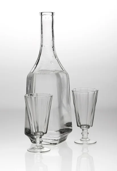 Dois copos e um decantador sobre fundo branco cinzento — Fotografia de Stock