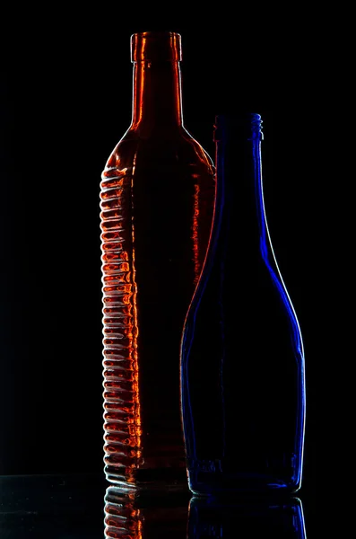 Garrafa vermelha e garrafa azul em um fundo preto — Fotografia de Stock