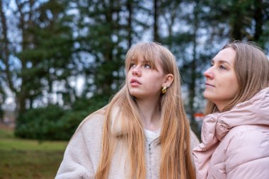 Anne ve kızı açık havada özel bir anı paylaşıyor, merakla bakıyor, yemyeşil ile çevrili, onların yakın ilişkilerini ve doğayla ilişkilerini sembolize ediyor