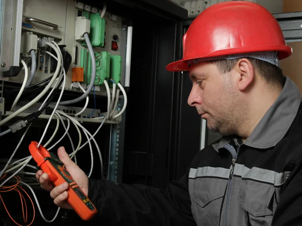 Trabajador en casco rojo hacer mediciones eléctricas — Foto de Stock