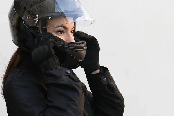 Attractive girl motorcyclist in black take on a helmet — Stock Photo, Image