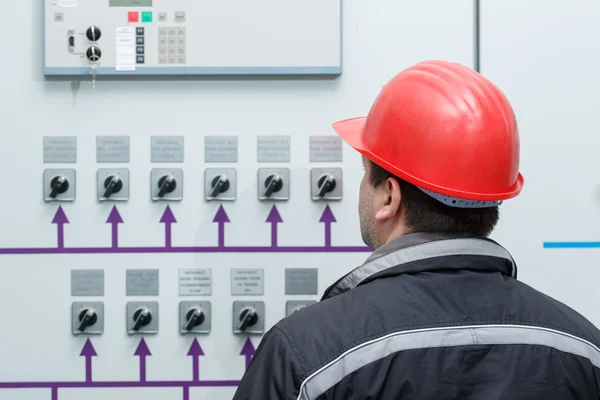 Technician reading instruments in power plant control center