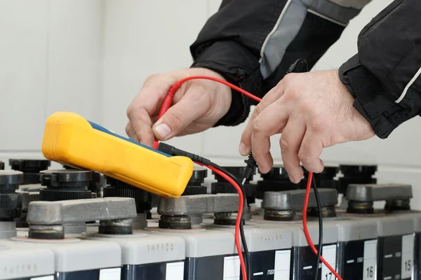 Elektriker überprüfen Batterie mit gelbem Multimeter — Stockfoto