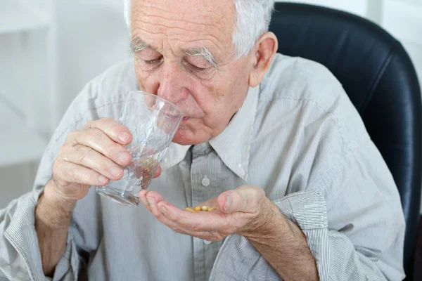 Old man drinking pills — Stock Photo, Image