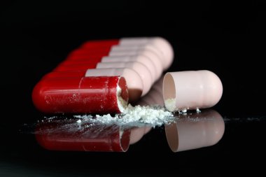 Kırmızı ve pembe antibiyotik kapsül siyah yansıma ile kırık