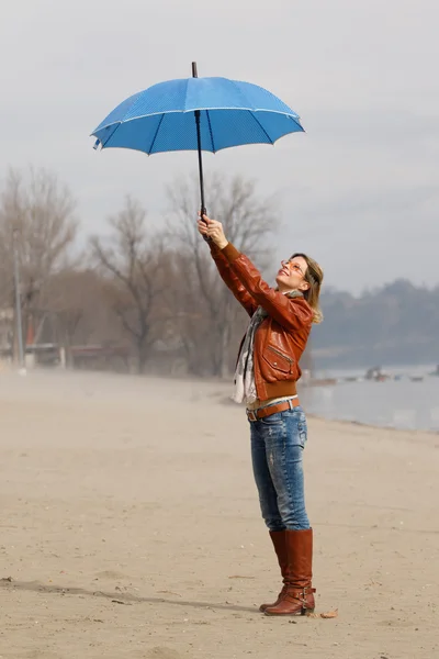 Rüzgarlı bir gün mavi şemsiyesi olan kadın — Stok fotoğraf