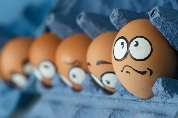 Fila de tristes caras de huevo asustadas en panel azul — Foto de Stock